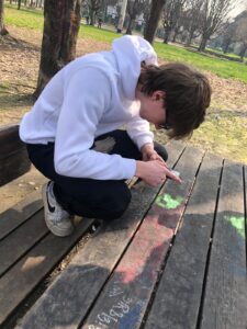 Uno studente osserva una macchia su un tavolo del parco
